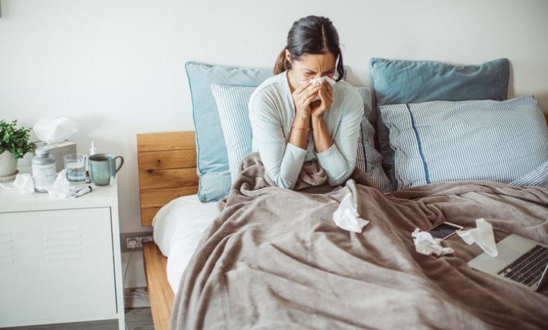 Woman sitting up in bed and blowing her nose to clear congestion on one side