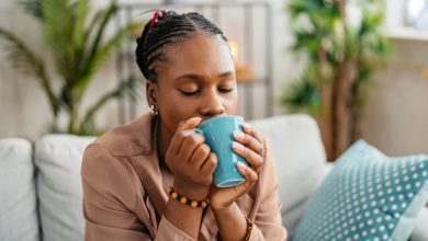 Woman sitting on the sofa in the living room, drinking protein coffee.