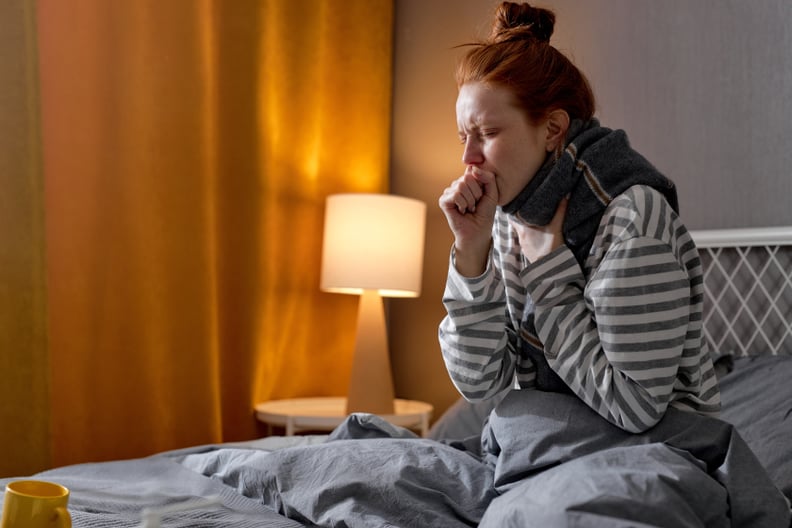 Woman sitting in bed, coughing at night.