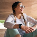 Woman in fitness clothes sitting and looking proud after accomplishing a goal through mindset training