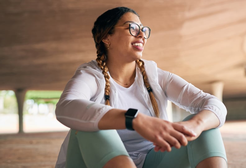 Woman in fitness clothes sitting and looking proud after accomplishing a goal through mindset training