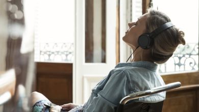 Woman sitting in a chair while wearing headphones and listening to music with eyes closed.