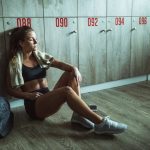 Tired female athlete resting on a break at gym's locker room.