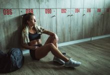 Tired female athlete resting on a break at gym's locker room.