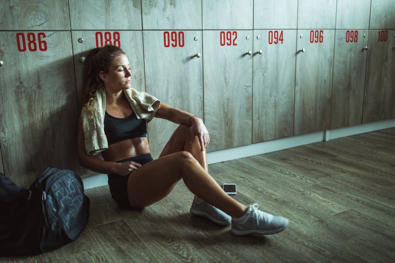 Tired female athlete resting on a break at gym's locker room.