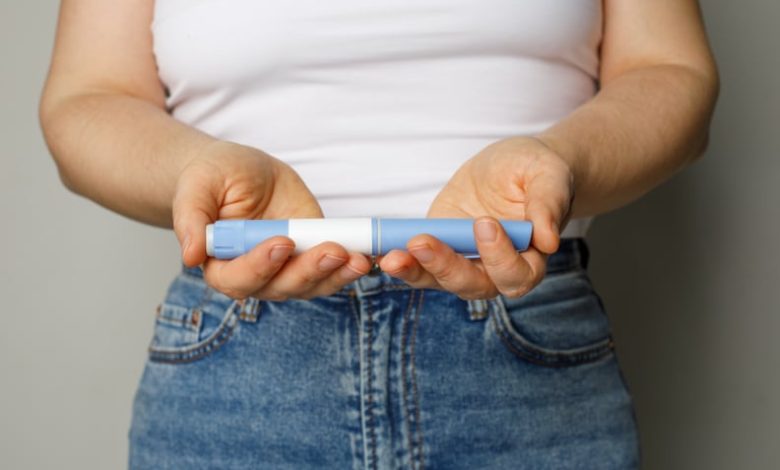 Close-up of a woman holding a blue Wegovy injection pen.