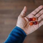 Close-up of unrecognizable woman holding four melatonin gummy supplements in the palm of her hand.