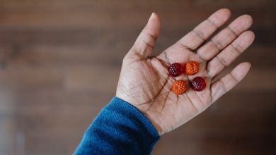 Close-up of unrecognizable woman holding four melatonin gummy supplements in the palm of her hand.