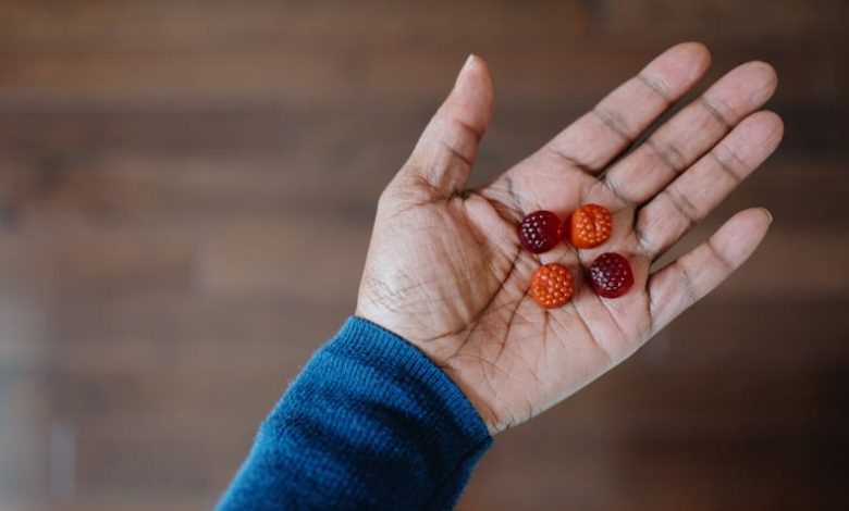 Close-up of unrecognizable woman holding four melatonin gummy supplements in the palm of her hand.