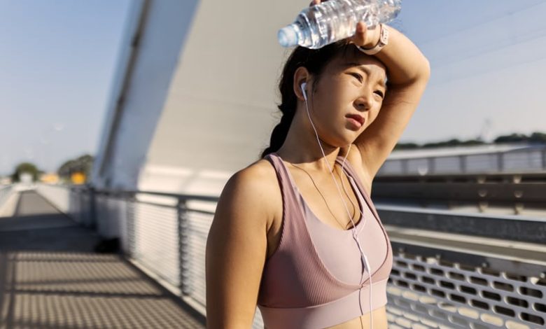 Young woman drinking water after exercising