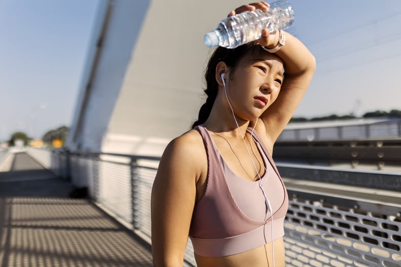 Young woman drinking water after exercising