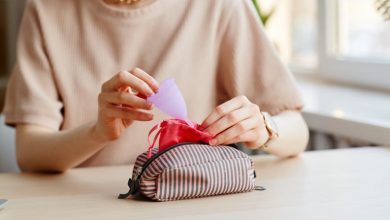 Woman putting menstrual cup in cosmetic bag with other essentials.