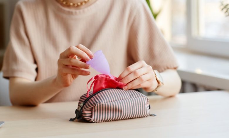 Woman putting menstrual cup in cosmetic bag with other essentials.