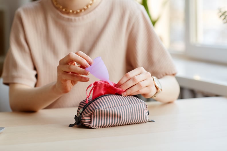 Woman putting menstrual cup in cosmetic bag with other essentials.