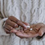 A woman's hands holding pills, contemplating when to take melatonin