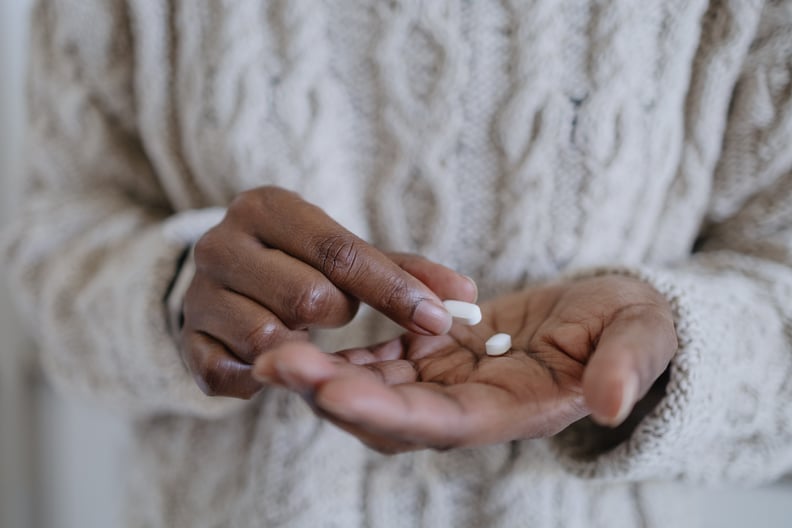 A woman's hands holding pills, contemplating when to take melatonin