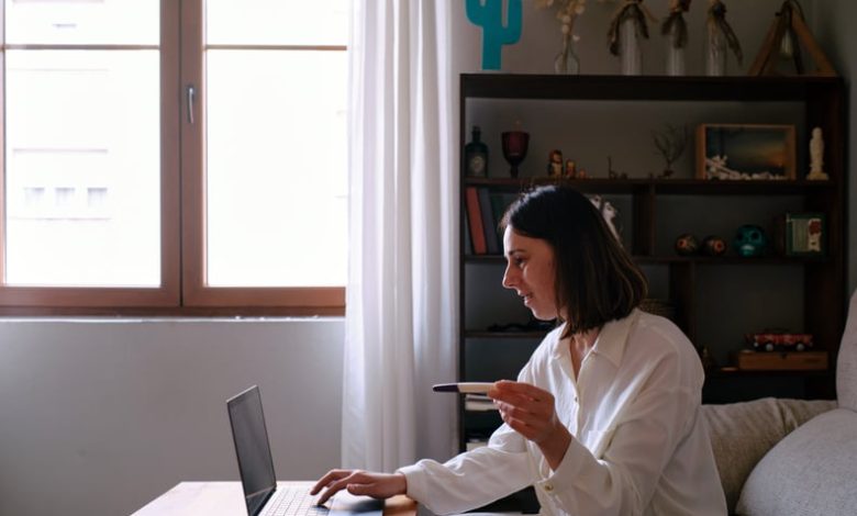 Woman looking at the computer sitting on the sofa at home searching the internet for pregnancy test instructions.