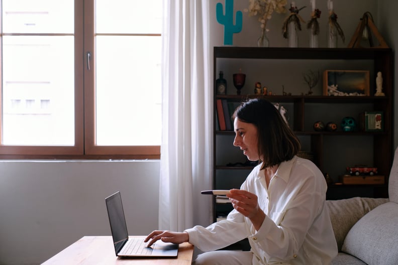 Woman looking at the computer sitting on the sofa at home searching the internet for pregnancy test instructions.