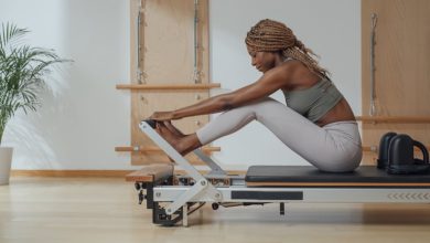 Beautiful African smiling sportswoman doing pilates exercise on reformer as part of the 3-2-1 workout method