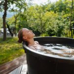 Woman sitting in an ice bath outdoors, enjoying the benefits of a cold plunge.