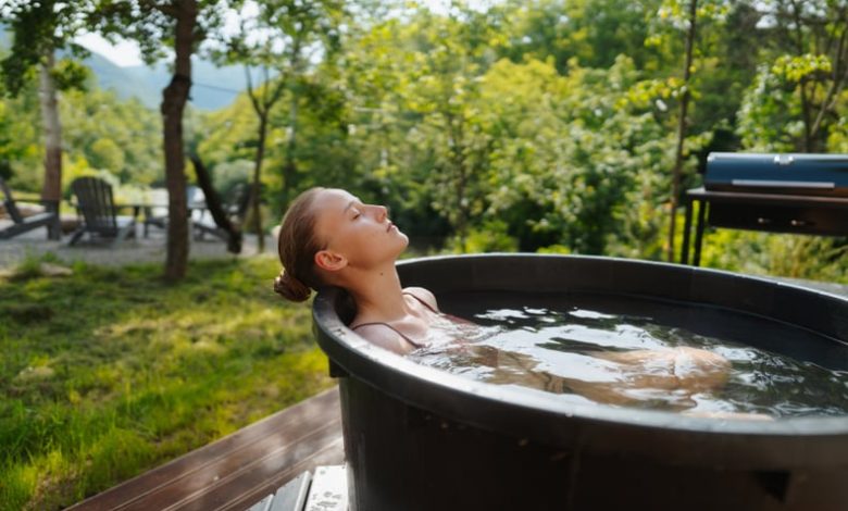 Woman sitting in an ice bath outdoors, enjoying the benefits of a cold plunge.