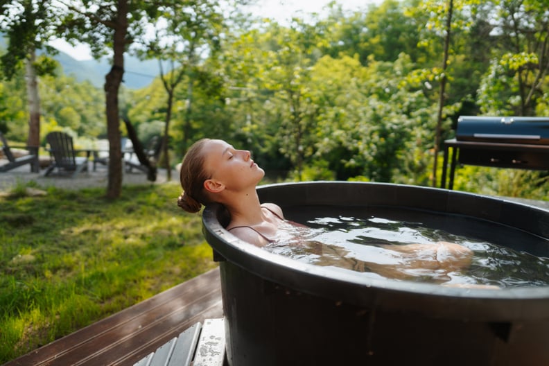 Woman sitting in an ice bath outdoors, enjoying the benefits of a cold plunge.