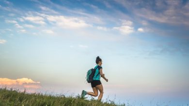 Young woman running in the mountains with backpack on her shoulders.