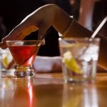 Woman with alcoholic drinks at a bar, benefits of dry January.