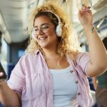 Woman listening to music through her phone and reviewing her Spotify Wrapped, while on the bus.