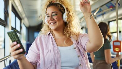 Woman listening to music through her phone and reviewing her Spotify Wrapped, while on the bus.