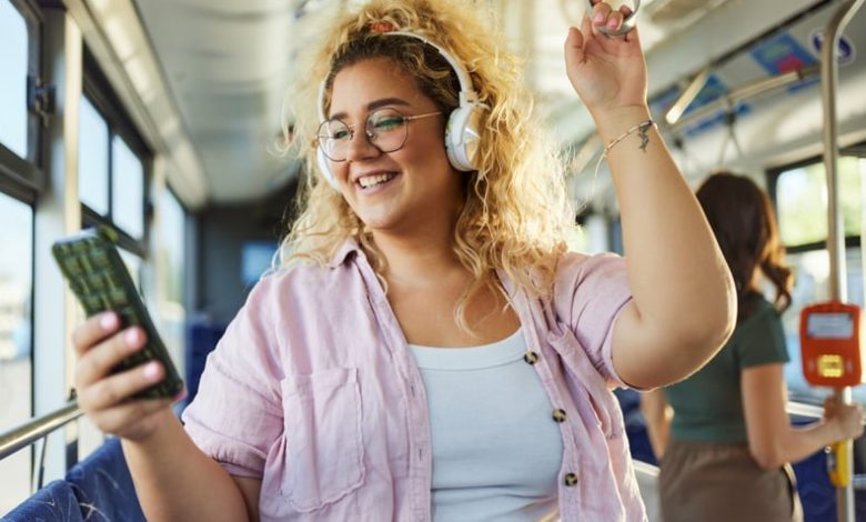 Woman listening to music through her phone and reviewing her Spotify Wrapped, while on the bus.