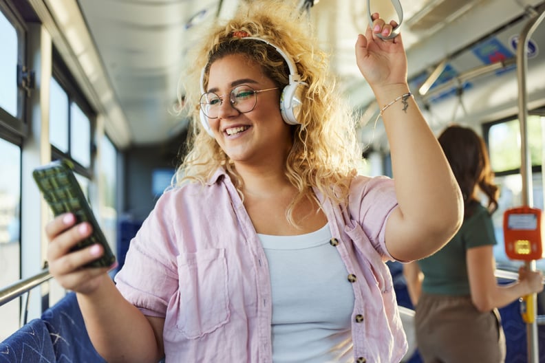 Woman listening to music through her phone and reviewing her Spotify Wrapped, while on the bus.