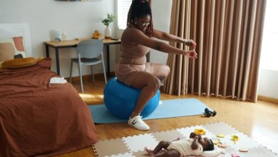 Happy mother of newborn baby exercising at home.