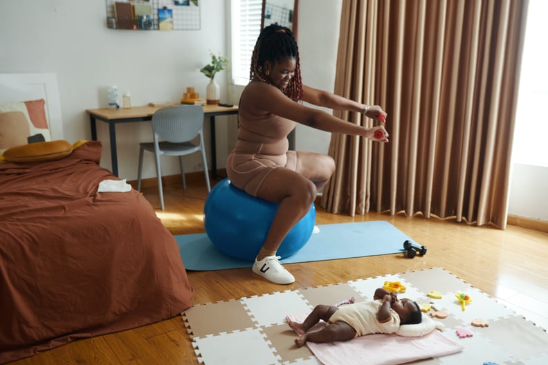 Happy mother of newborn baby exercising at home.