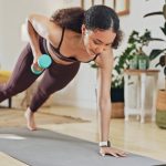 Woman starting to work out again, using dumbbells on her yoga mat.