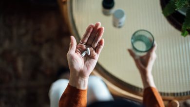 Woman taking medicine in hand with a glass of water, chronic illness during the holidays.