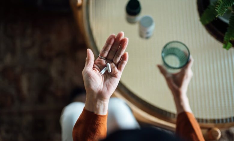 Woman taking medicine in hand with a glass of water, chronic illness during the holidays.