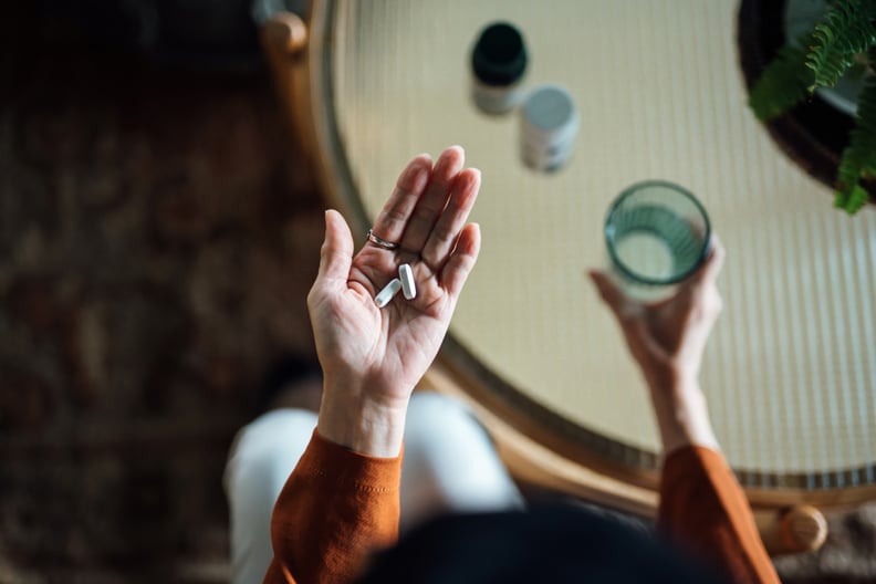 Woman taking medicine in hand with a glass of water, chronic illness during the holidays.